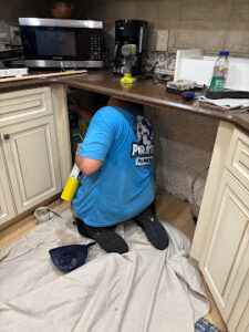 Plumber performing drain installation under bathroom sink in Dunedin, FL